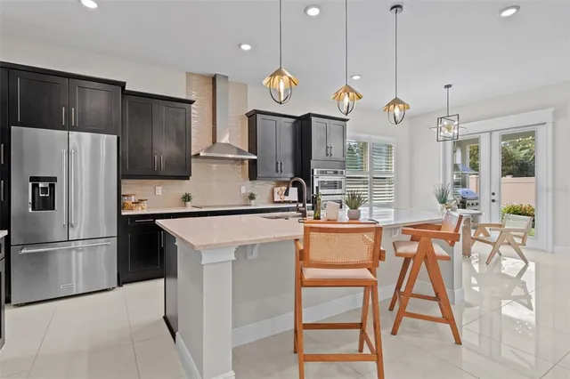 a kitchen with stainless steel appliances granite countertop a refrigerator a oven a sink a dining table and chairs with wooden floor