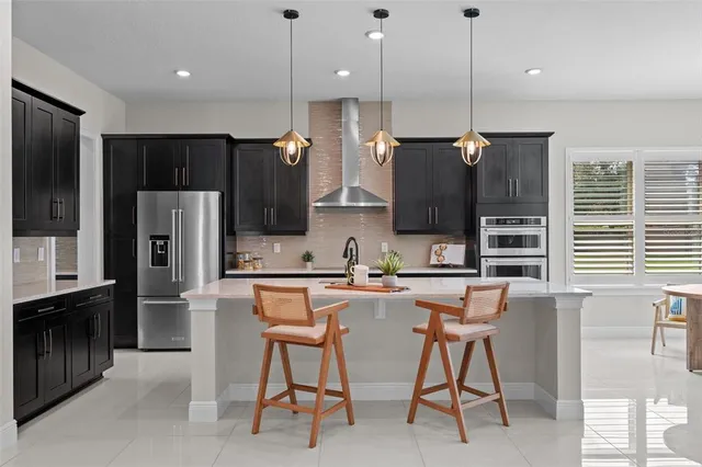 a kitchen with stainless steel appliances kitchen island granite countertop a refrigerator a stove a sink dishwasher with a dining table and chairs