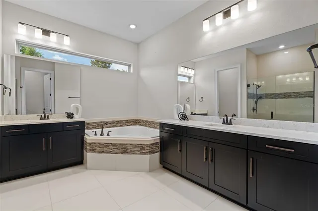 a spacious bathroom with a granite countertop bathtub sink double and mirror