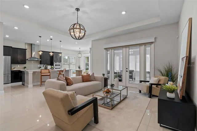 a living room with furniture kitchen view and a chandelier
