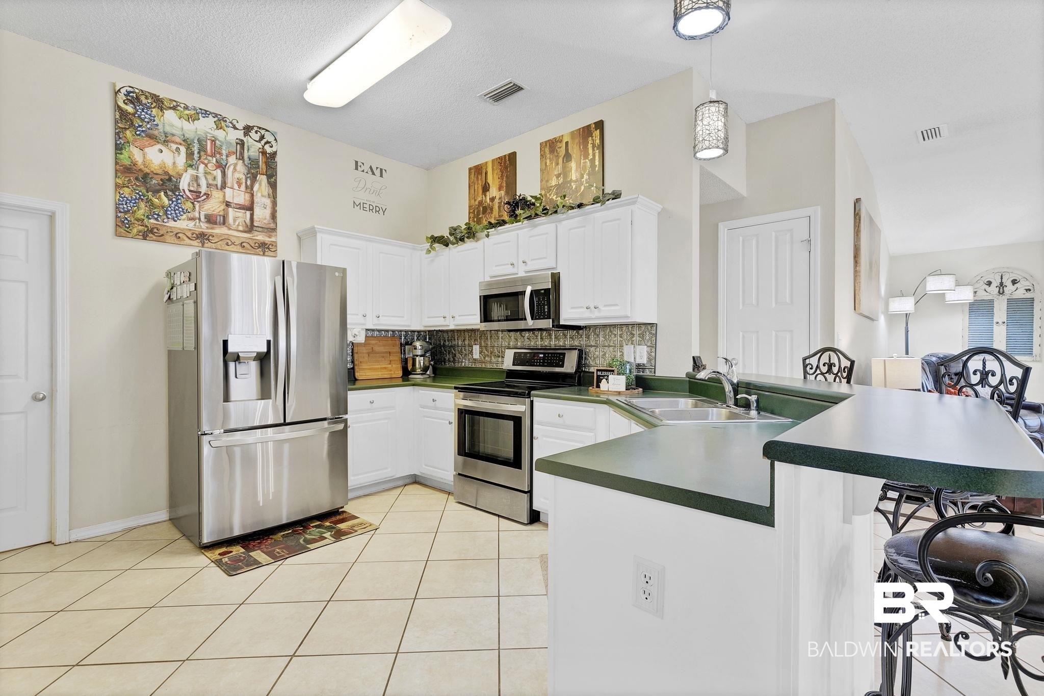 11103 Pontchartrain Loop Daphne, AL 36526 - Photo 16 of 29 Kitchen with backsplash, appliances with stainless steel finishes, a peninsula, light tile patterned flooring, and a sink