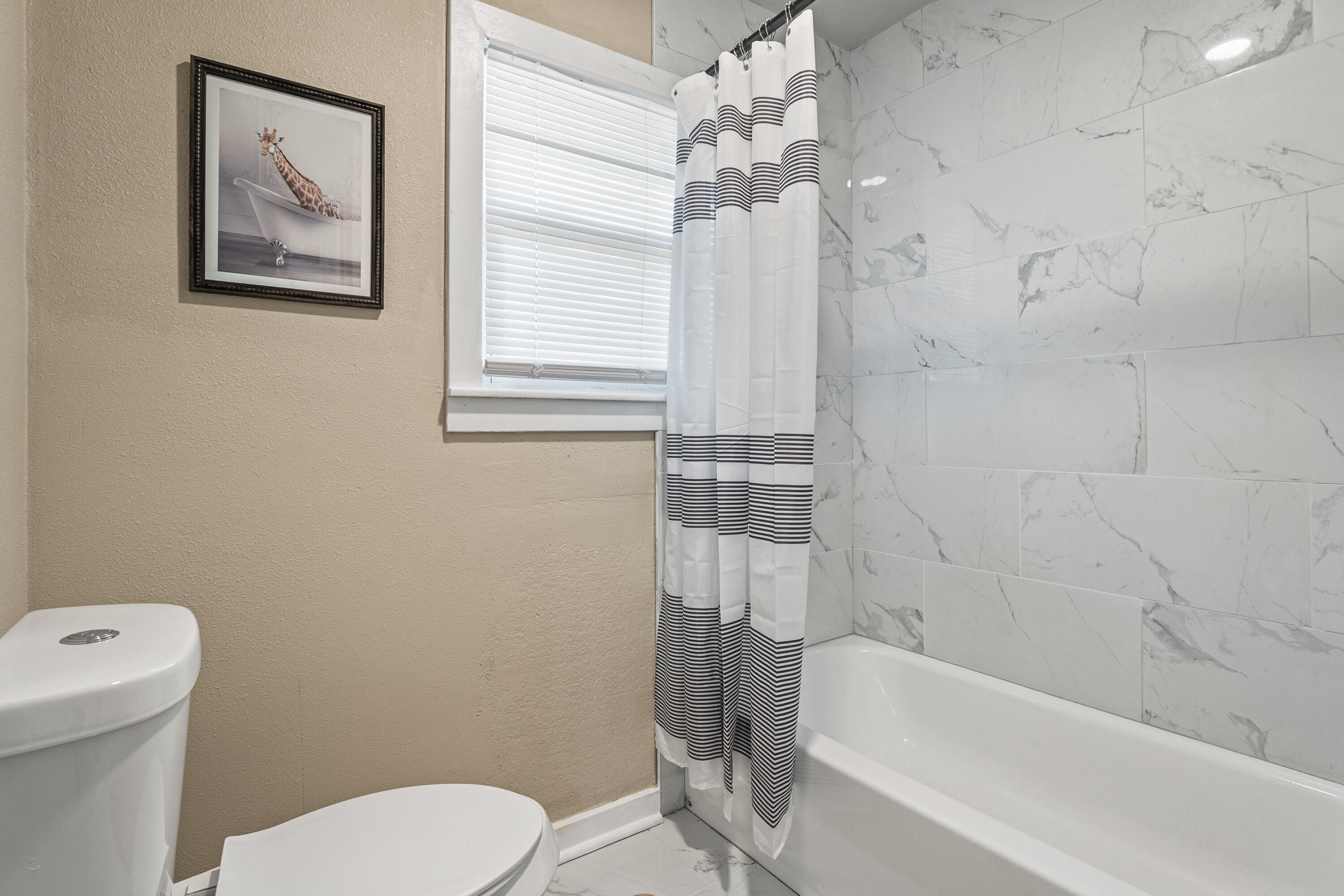 5217 9th Street Lubbock, TX 79416 - Photo 10 of 18 a bathroom with a toilet a sink and bathtub