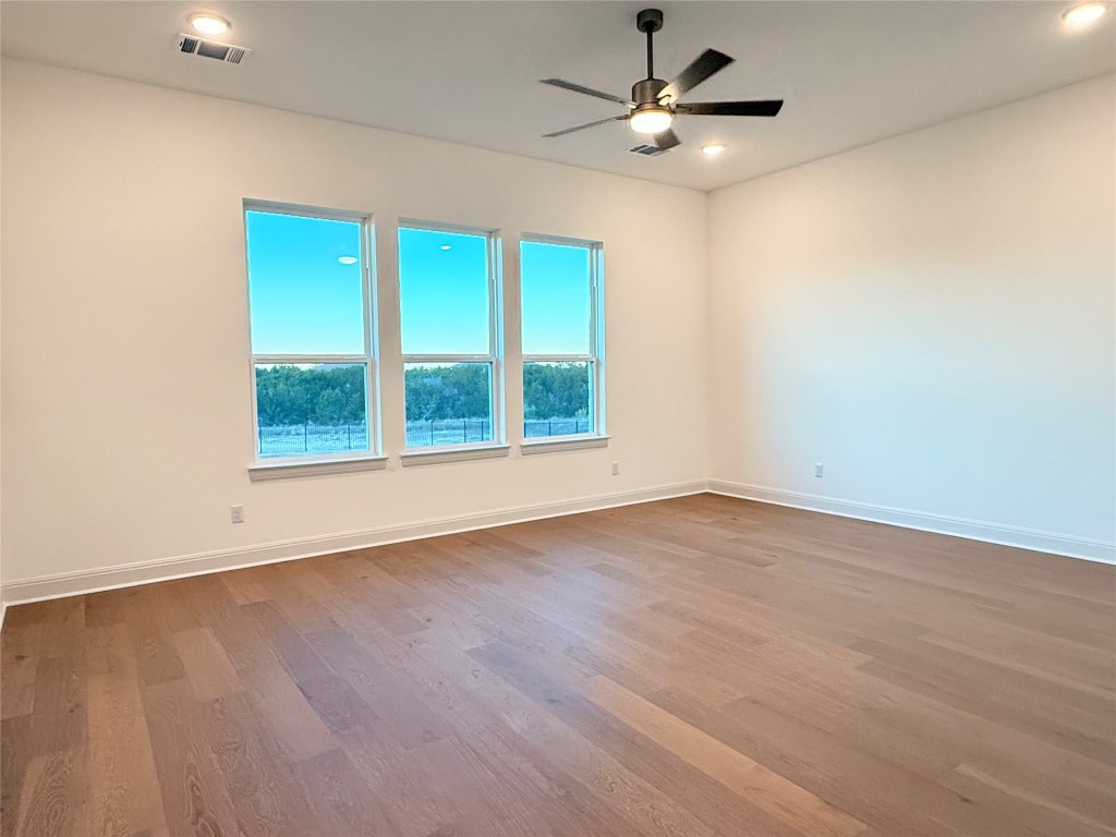 204 Rusty Colt Liberty Hill, TX 78642 - Photo 13 of 20 an empty room with wooden floor ceiling fan and windows