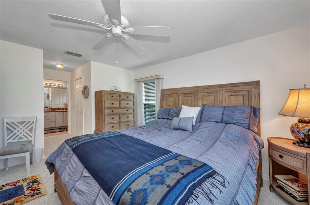 24419 Buckingham Way Punta Gorda, FL 33980 - Photo 13 of 40 a bedroom with a bed a dresser and a chandelier