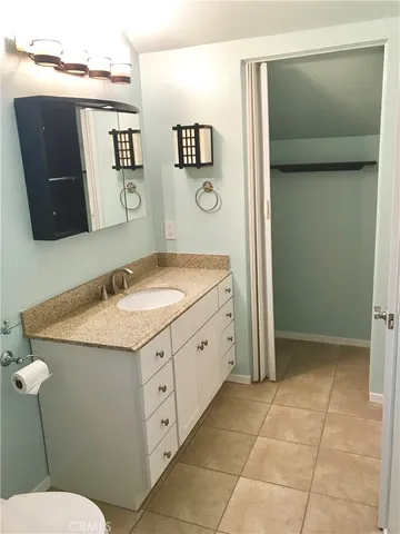 a bathroom with a granite countertop sink a mirror and a toilet