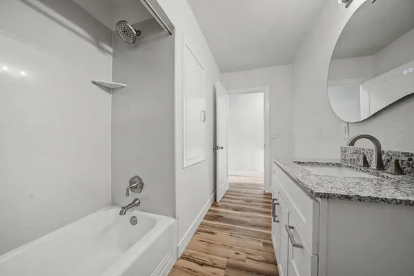 a view of empty room with wooden floor and fan
