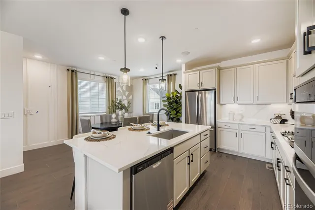 a kitchen that has a lot of white cabinets and stainless steel appliances