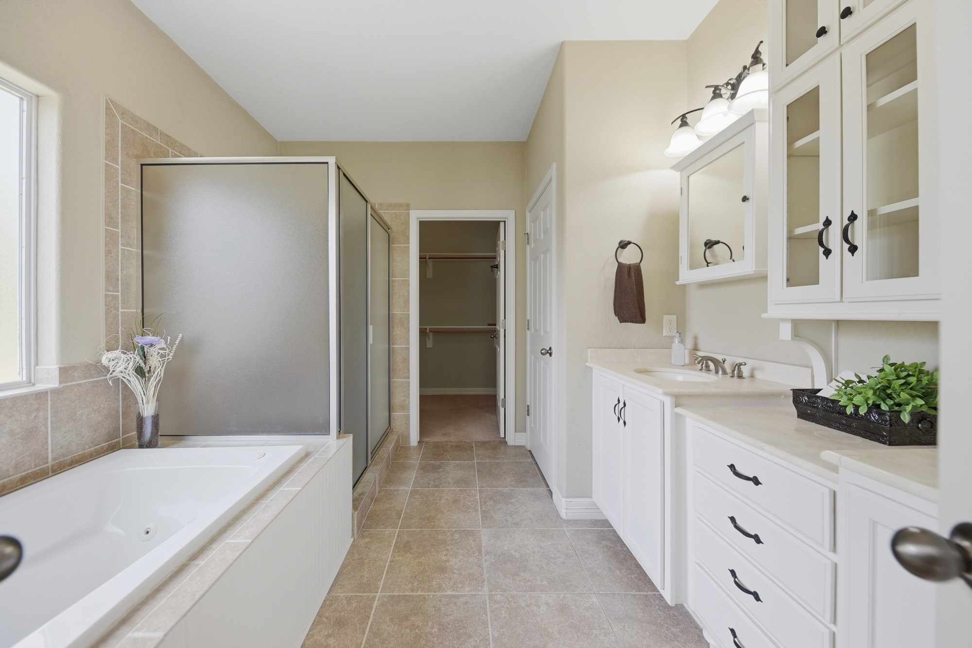 350 Owl Creek Road Giddings, TX 78942 - Photo 14 of 29 Full bath with vanity, a tub with jets, a stall shower, a spacious closet, and light tile patterned floors