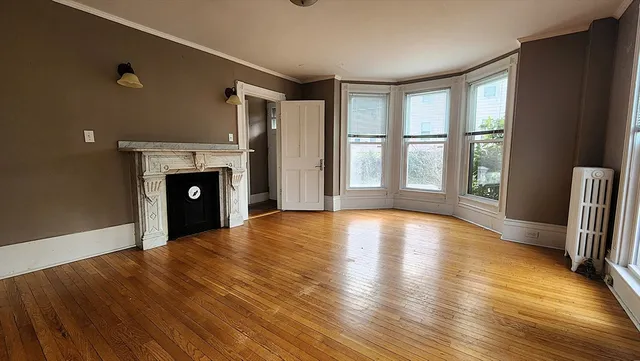 a view of empty room with wooden floor and fireplace