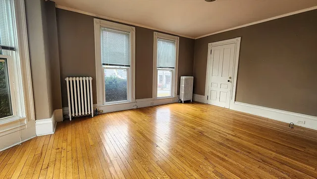 an empty room with wooden floor and windows