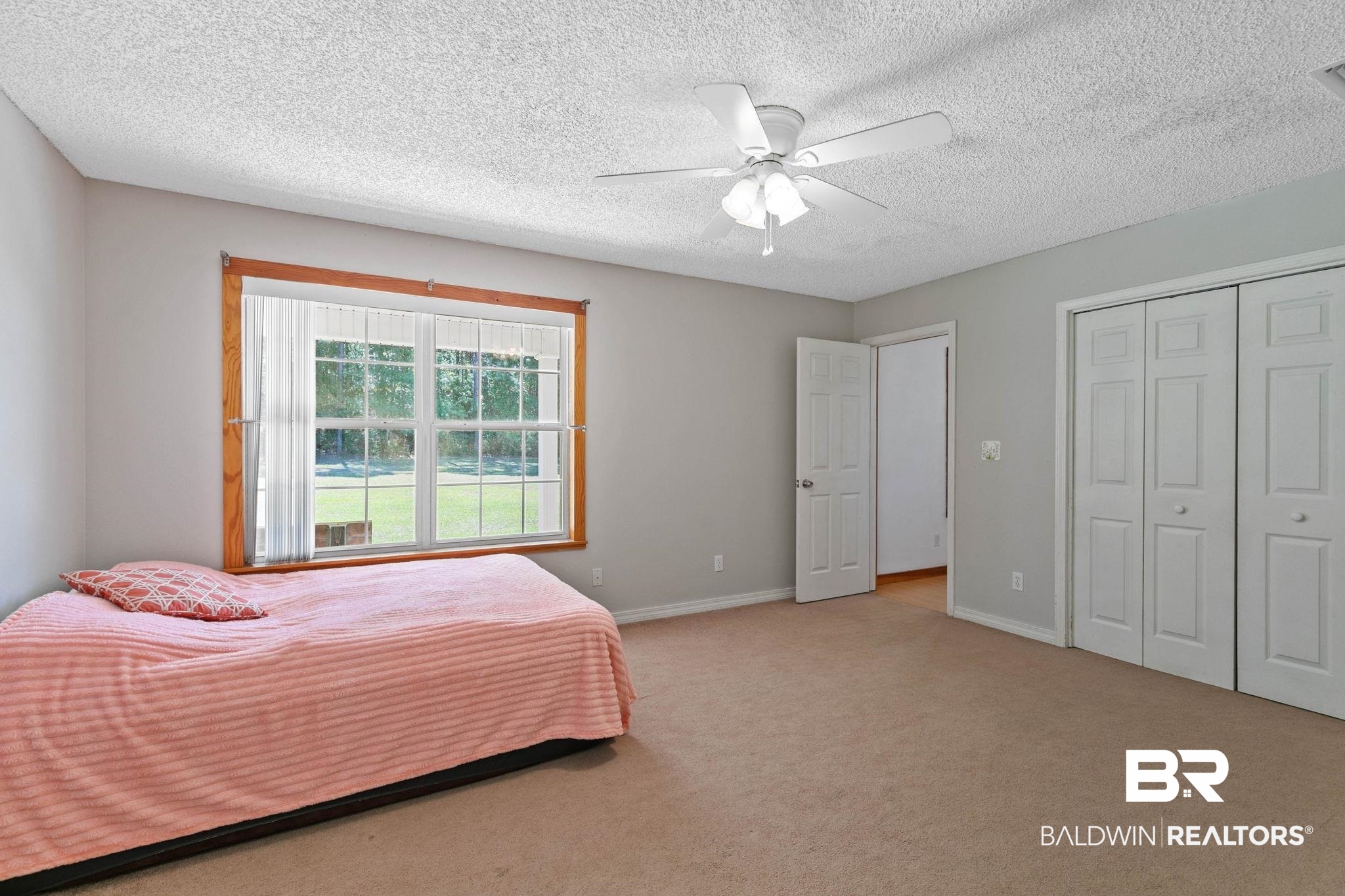 20219 Greek Cemetery Road Robertsdale, AL 36567 - Photo 27 of 41 Carpeted room featuring a large window with wooden trim, a ceiling fan with integrated lighting, and white bi-fold closet doors