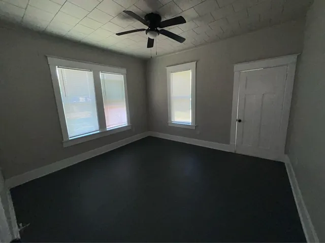 an empty room with a ceiling fan and a window