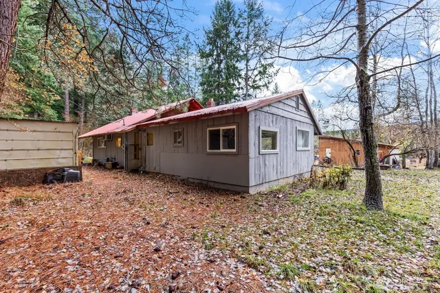 a backyard of a house with large trees and brick wall