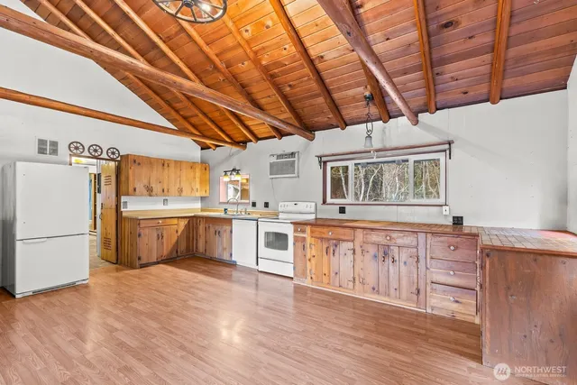 a large white kitchen with wooden floor and stainless steel appliances