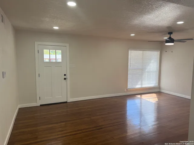 a view of an empty room with wooden floor and a window