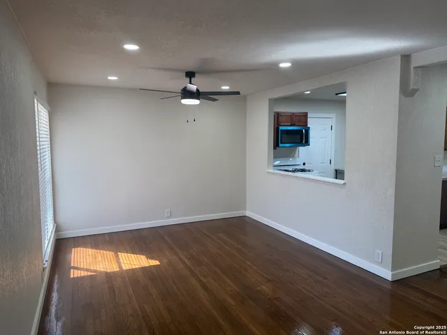an empty room with wooden floor and windows