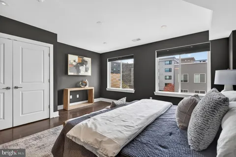 a bedroom with a bed a mirror on dresser and a wooden floor