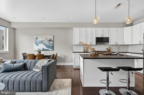 a living room with furniture a flat screen tv and kitchen area