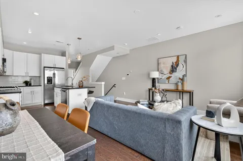a living room with couches chairs and kitchen view with wooden floor