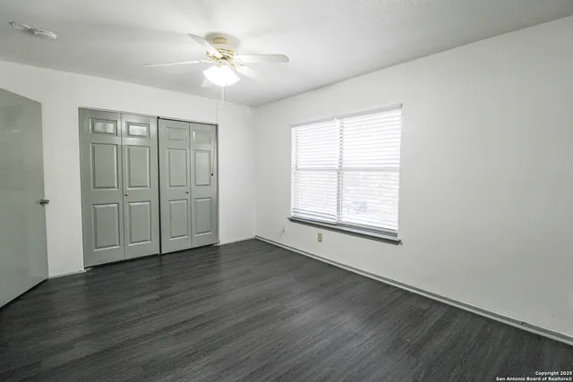 an empty room with wooden floor and a ceiling fan