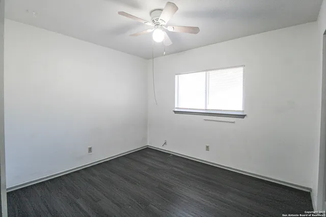 an empty room with wooden floor and fan