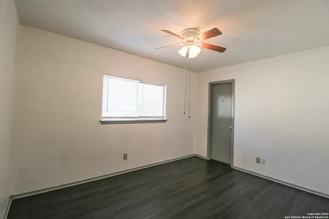 an empty room with wooden floor and a ceiling fan