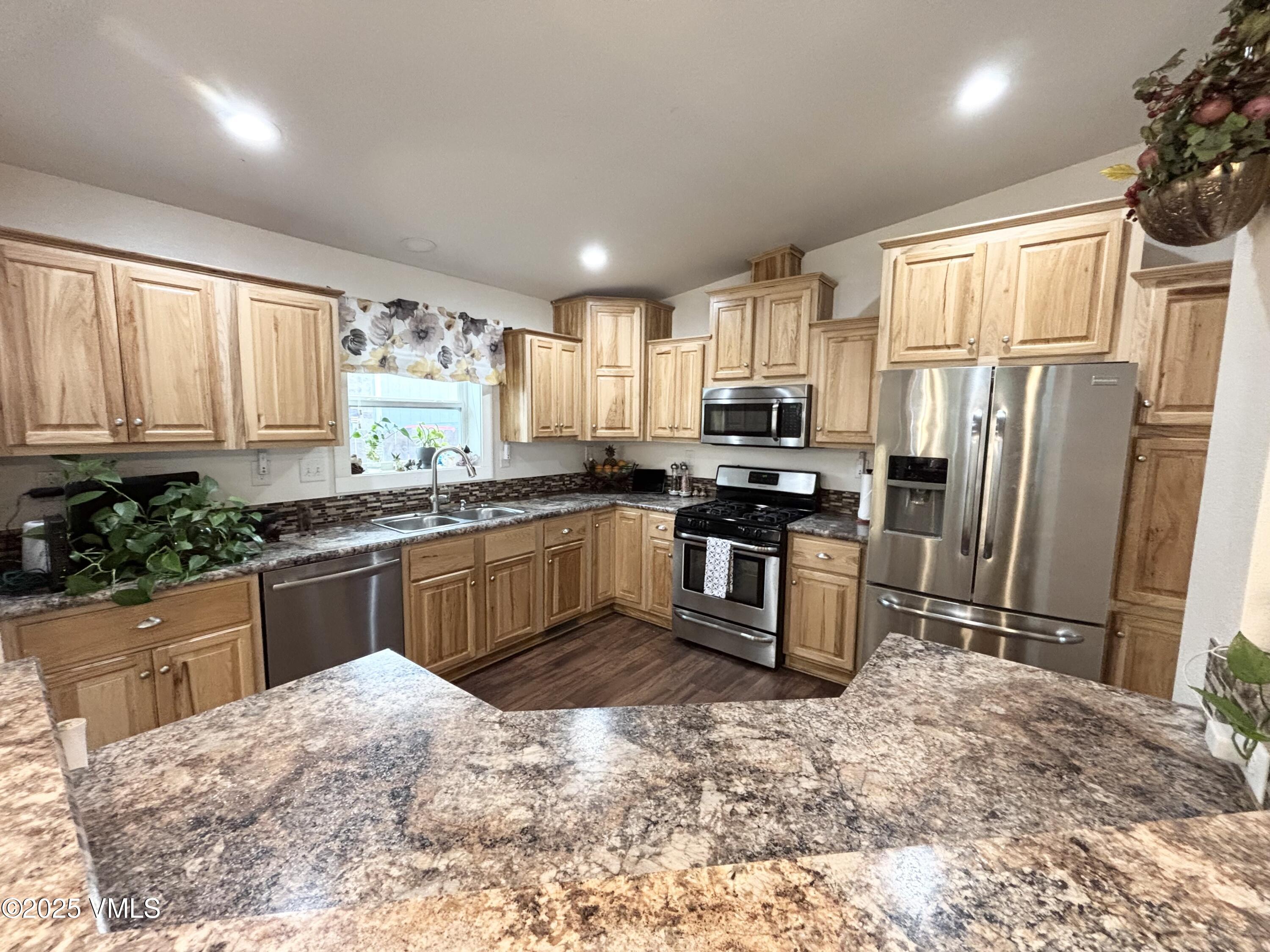 66 Bluegill Loop Gypsum, CO 81637 - Photo 7 of 37 a kitchen with stainless steel appliances granite countertop a refrigerator a sink a stove a microwave a refrigerator and cabinets