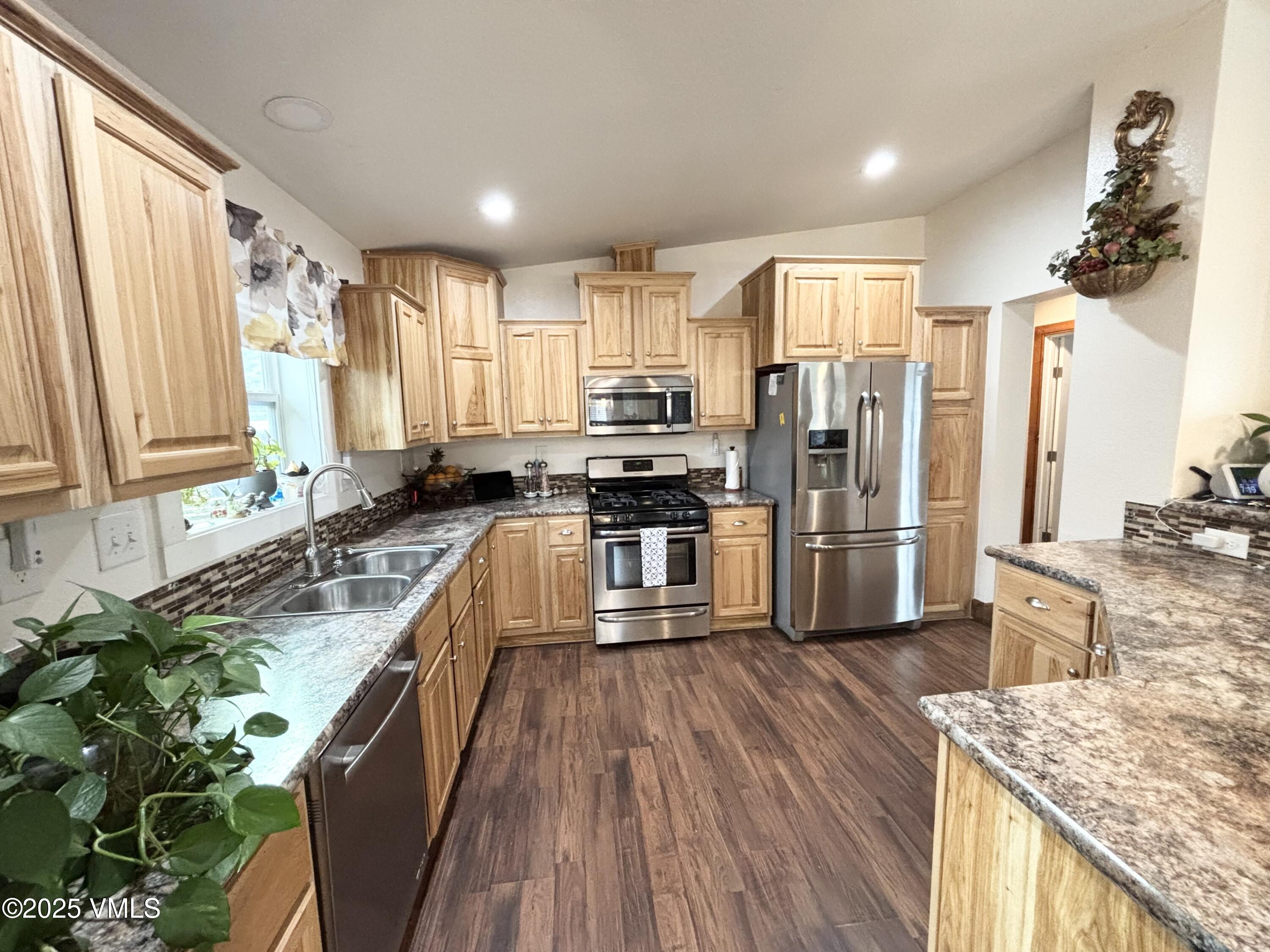 66 Bluegill Loop Gypsum, CO 81637 - Photo 8 of 37 a kitchen with stainless steel appliances granite countertop a refrigerator a sink dishwasher a stove and white countertops with wooden floor