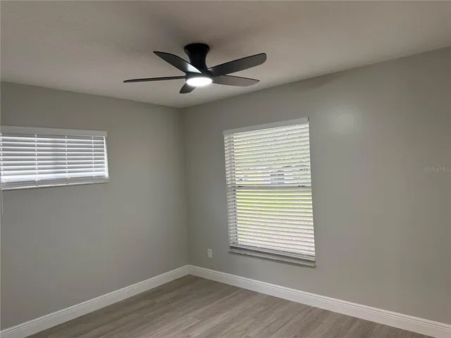 a view of a big room with wooden floor and windows