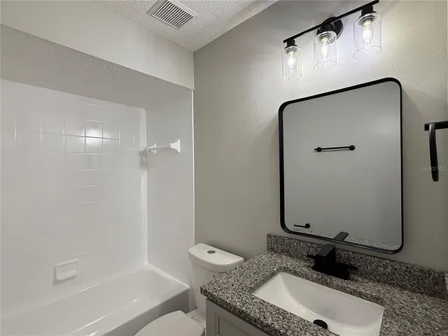 a bathroom with a granite countertop sink a mirror and shower