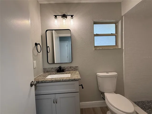 a bathroom with a granite countertop toilet sink and mirror