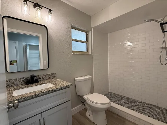 a bathroom with a granite countertop sink toilet and shower