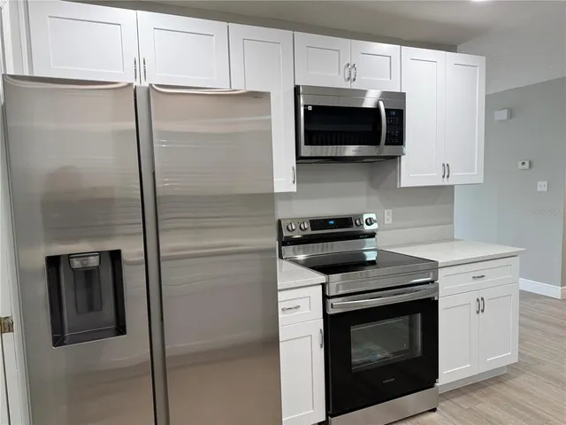 a kitchen with stainless steel appliances white cabinets and a stove a refrigerator with wooden floor