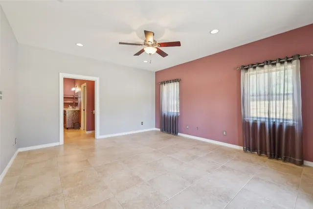 an empty room with windows and fan