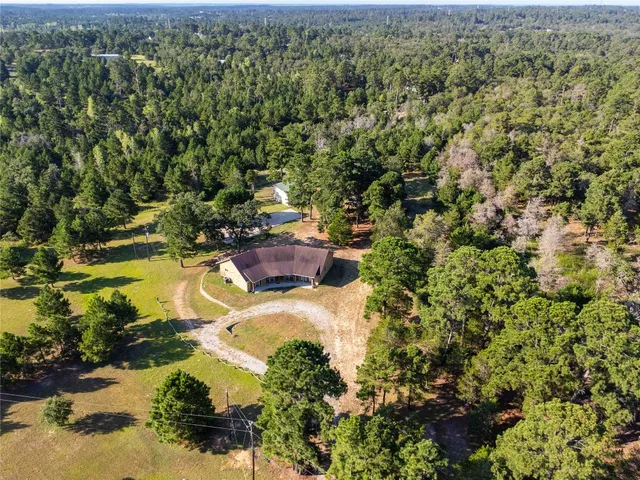 an aerial view of residential house with outdoor space and trees all around
