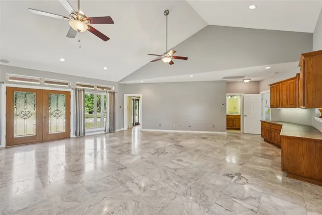 a view of an empty room with a window and a kitchen