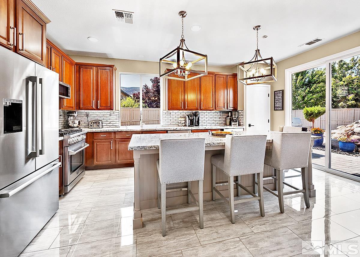 2552 Country Falls Lane Reno, NV 89521 - Photo 6 of 40 a kitchen with stainless steel appliances a dining table chairs and granite counter tops