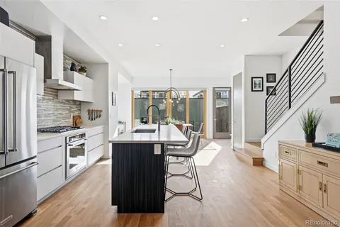 a kitchen with stainless steel appliances a dining table chairs stove refrigerator and cabinets