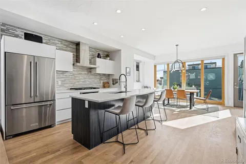 a kitchen with stainless steel appliances granite countertop a table chairs and a refrigerator