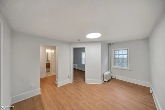a view of an empty room with window and wooden floor