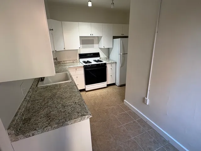 a kitchen with granite countertop a sink stove and refrigerator