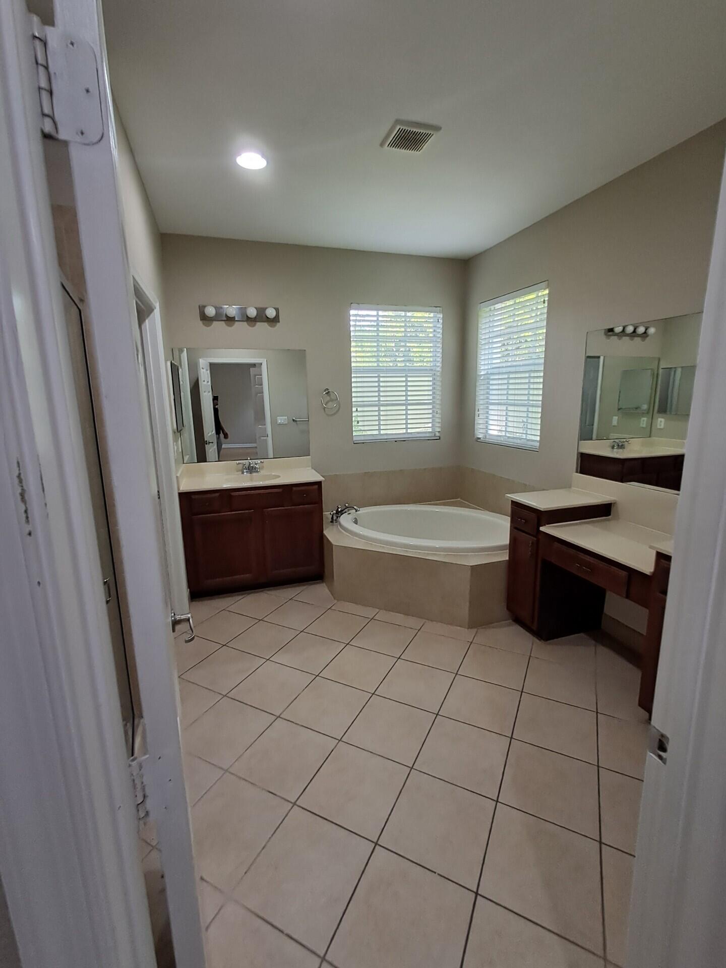 6729 Bulrush Court Greenacres, FL 33413 - Photo 34 of 35 a bathroom with a bathtub sink and mirror