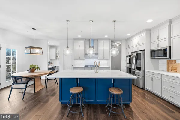 a kitchen with stainless steel appliances kitchen island granite countertop a sink a stove a dining table and chairs