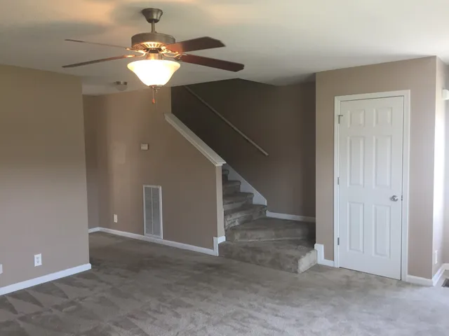 a view of an empty room with a chandelier fan