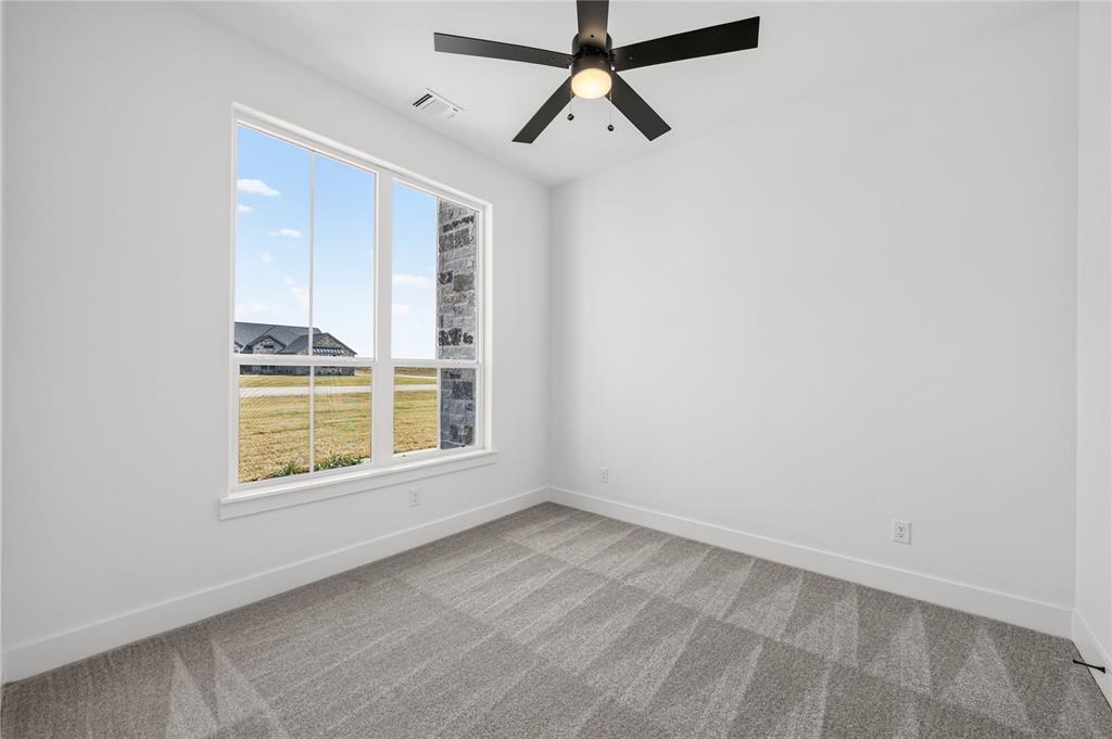 114 Red Bud Road Boyd, TX 76023 - Photo 25 of 32 Room featuring a large multi-pane window, patterned grey carpet, white baseboards, and a ceiling fan with light fixture