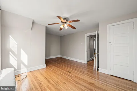 a view of empty room with wooden floor and fan