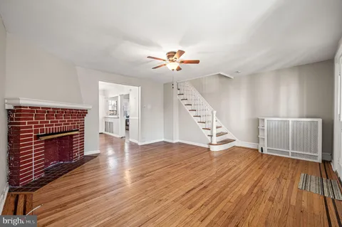 an empty room with wooden floor a ceiling fan and a fireplace