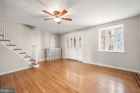 a view of an empty room with wooden floor and a ceiling fan