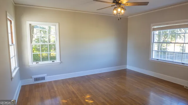 an empty room with wooden floor and windows