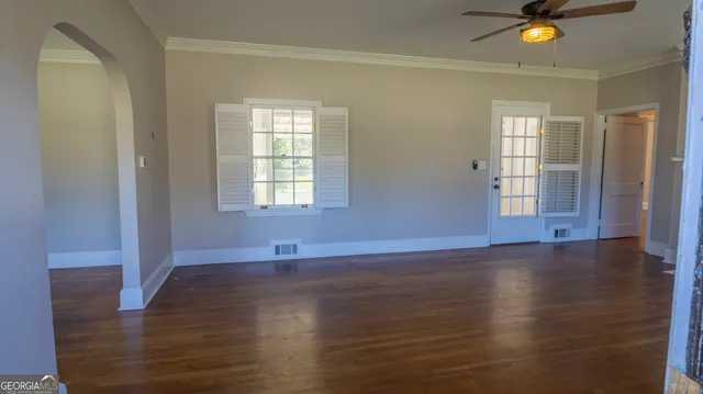 a view of an empty room with wooden floor and a window